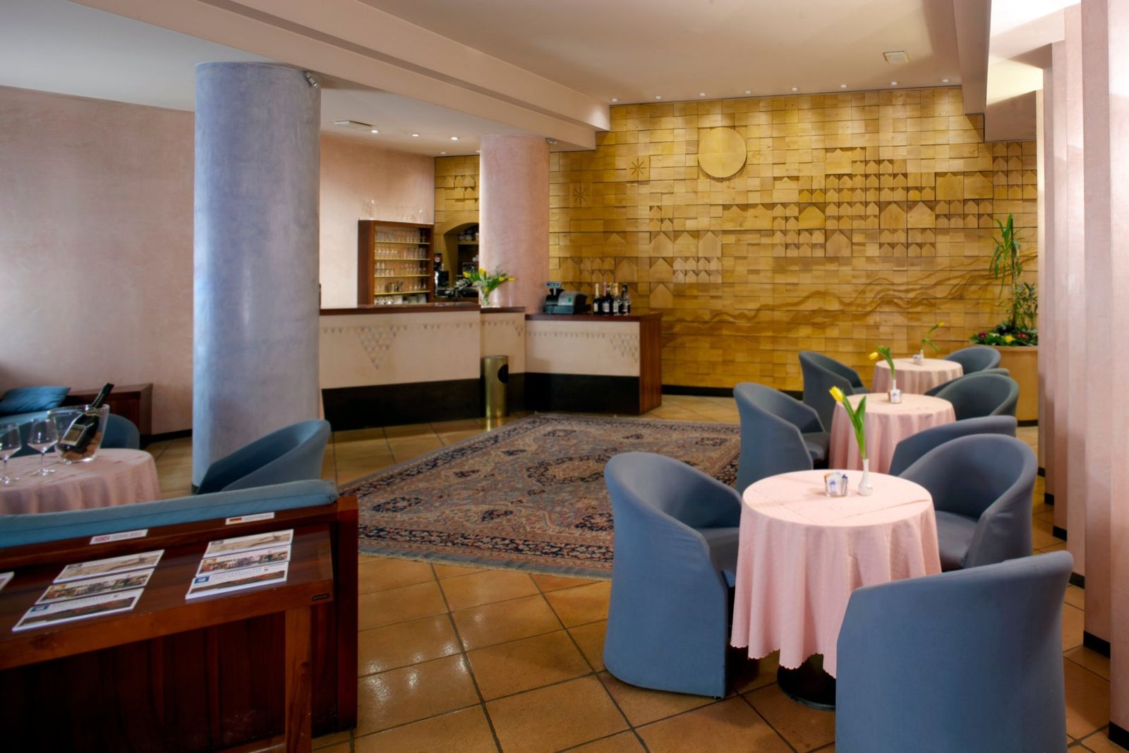 La hall con il bar, le poltrone azzurre e la parete in legno