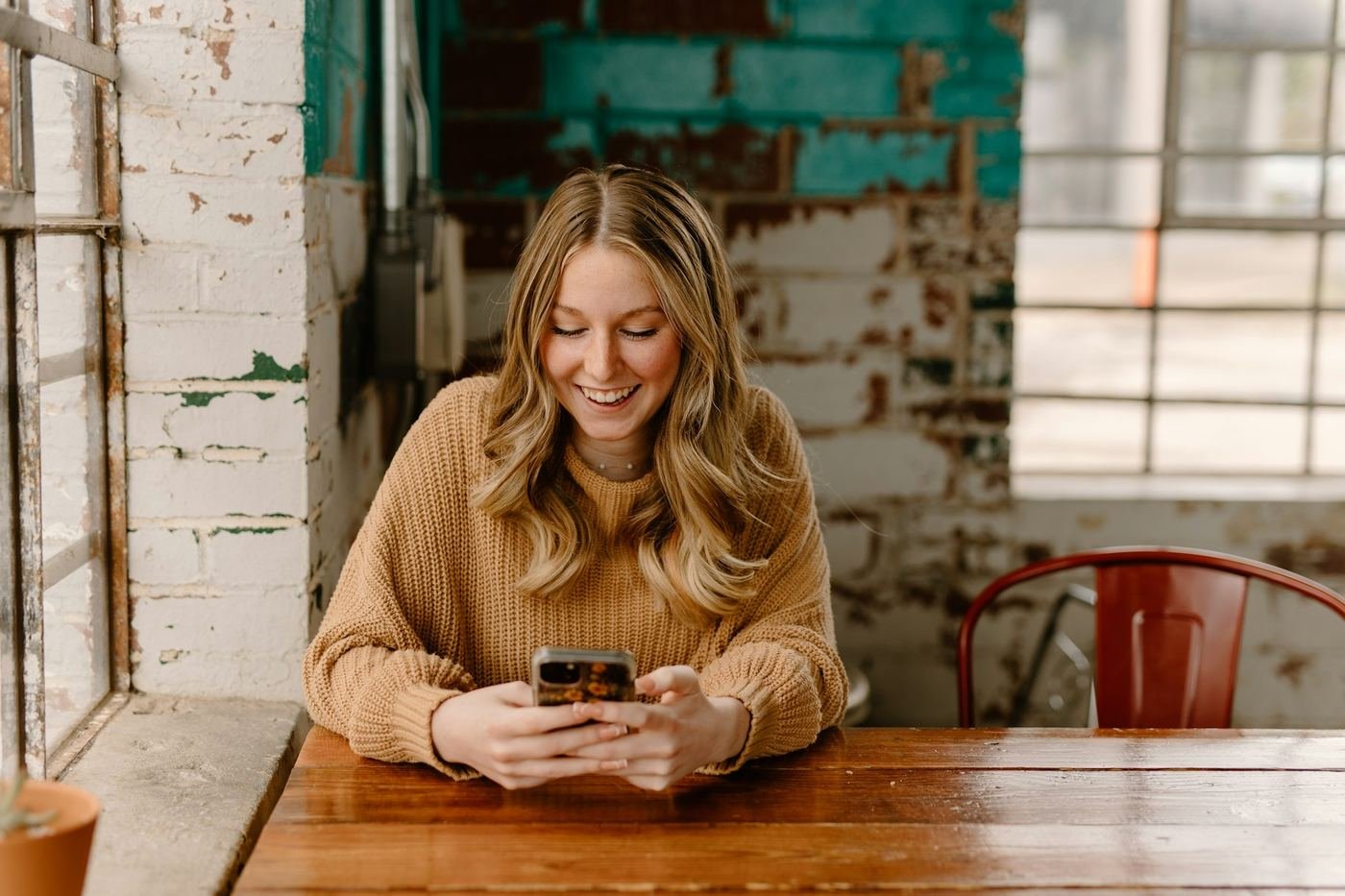 Una donna sorride leggendo il telefono in un caffè