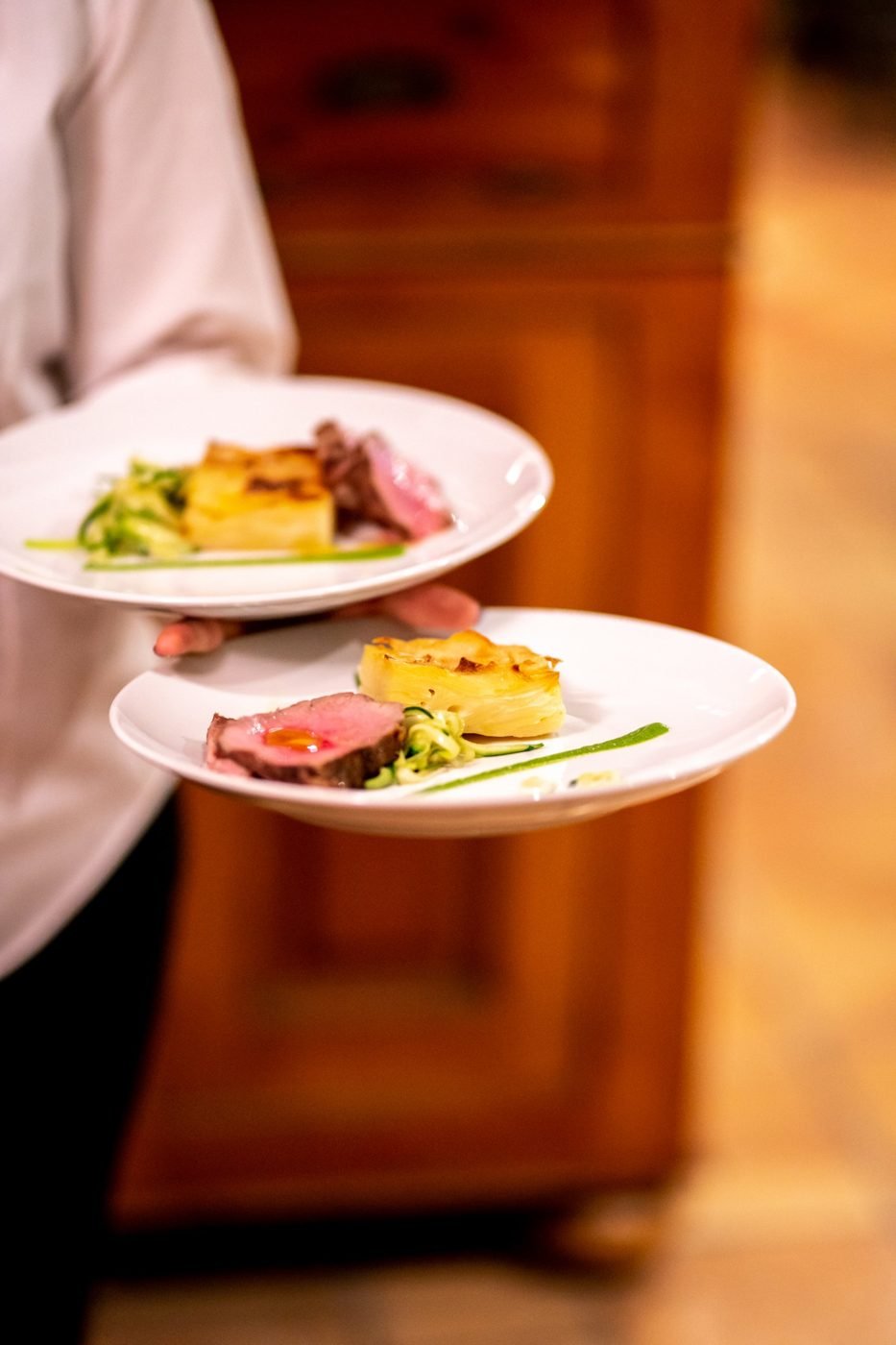 Due piatti di filetto con patate e zucchine portati in sala